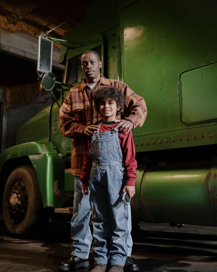 Truck driver with his son in front of a green semi
